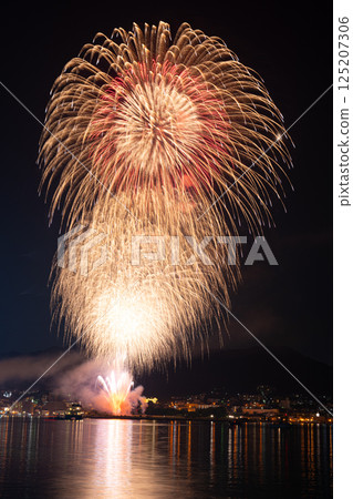 A fireworks display that lights up the mountains and townscape on a summer night 125207306
