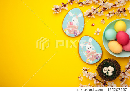 Easter gingerbread and eggs with seasonal flowers on yellow background. Sweet Easter concept, greeting card Easter gingerbread and eggs with seasonal flowers on yellow background. Sweet Easter concept, greeting card 125207367
