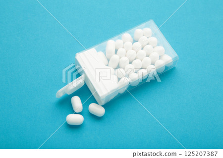 Tasty mint dragee candies with box on blue background. Tasty mint dragee candies with box on blue background. 125207387
