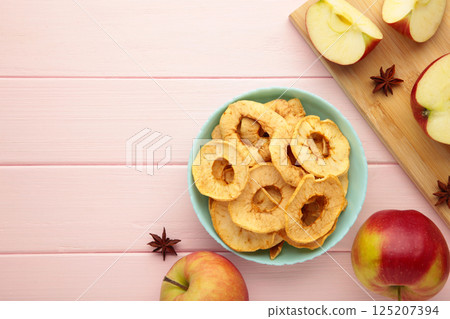Dried apple chips with cinnamon and star anise with fresh apple. Homemade dried organic apple sliced on pink wooden background. 125207394