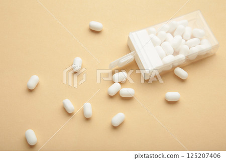 Candy in a box on beige background. Top view of the scattered dragees. 125207406