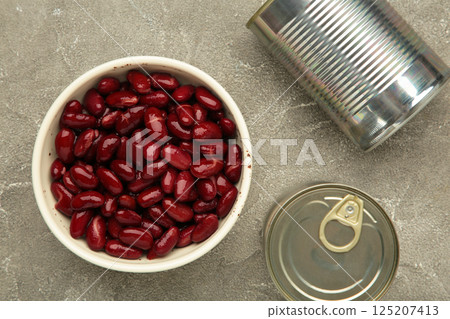 Red kidney beans in bowl and cans on grey background. Red kidney beans in bowl and cans on grey background. 125207413