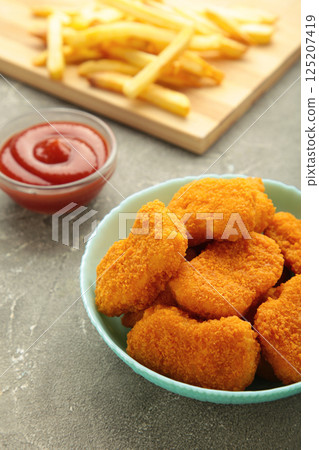 Homemade chicken nuggets and french fries with ketchup on grey background. Vertical photo Homemade chicken nuggets and french fries with ketchup on grey background. Vertical photo 125207419
