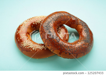 Fresh bread bagels with seed on blue background. Fresh bread bagels with seed on blue background. 125207433