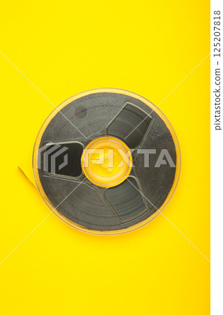 Film reel on yellow background. Vertical photo 125207818