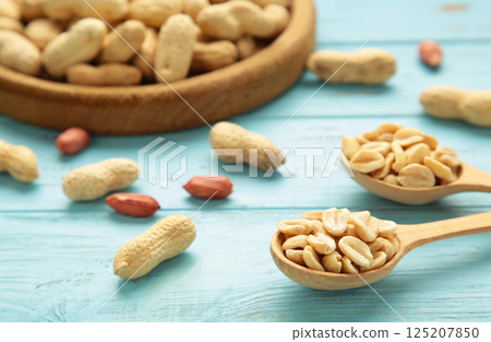 Fresh healthy peanuts in bowl and spoon on blue wooden background. Fresh healthy peanuts in bowl and spoon on blue wooden background. 125207850