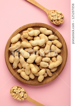 Fresh healthy peanuts in bowl and spoon on pink background. Fresh healthy peanuts in bowl and spoon on pink background. 125207856