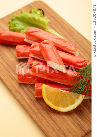 Fresh crab sticks with lemon on cutting board on beige background. Fresh crab sticks with lemon on cutting board on beige background. 125207871