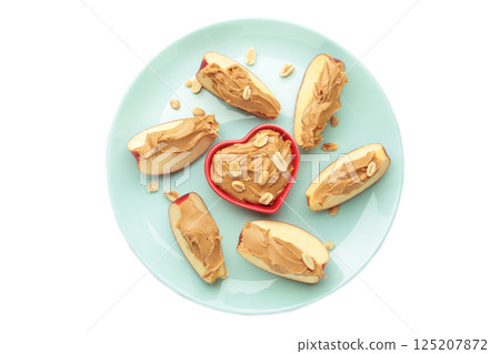 Slices of fresh apple with peanut butter in bowl on mint plate isolated on white background. Top view 125207872