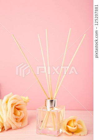 Aromatic reed air freshener and rose on pink background. Space for text. Vertical photo 125207881