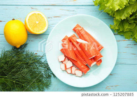 Cut crab sticks in bowl on blue wooden background. Cut crab sticks in bowl on blue wooden background. 125207885