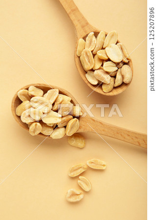 Peanuts in spoon on beige background. Vertical photo Peanuts in spoon on beige background. Vertical photo 125207896