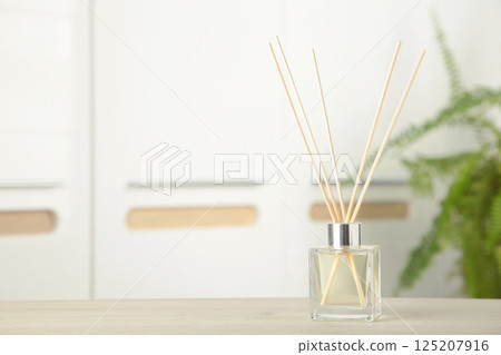 Aroma sticks in glass bottle. Aroma diffuser on table in room 125207916
