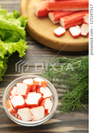 Cut crab sticks in bowl on brown wooden background. Vertical photo Cut crab sticks in bowl on brown wooden background. Vertical photo 125207917
