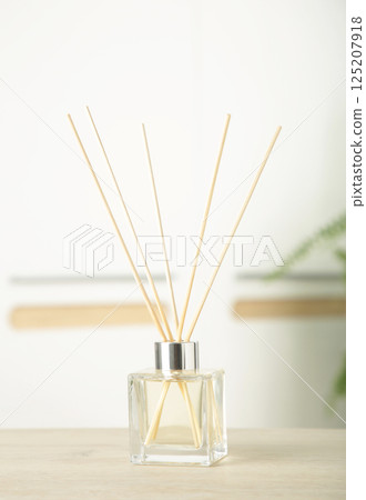 Aroma sticks in glass bottle. Aroma diffuser on table in room. Vertical photo 125207918