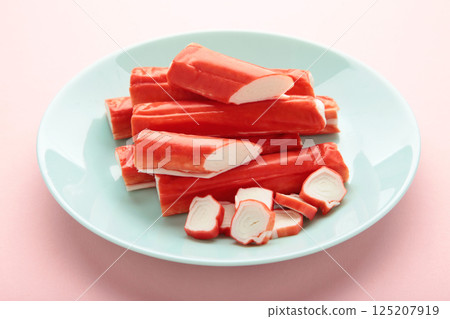 Tasty cut and whole crab sticks on mint table on pink background 125207919