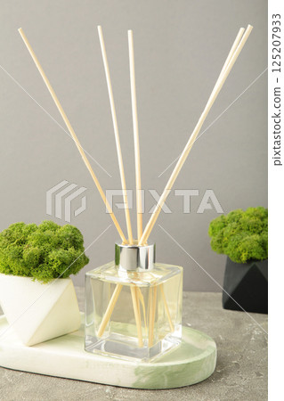 Aromatic reed air freshener and green plant on grey background Aromatic reed air freshener and green plant on grey background 125207933