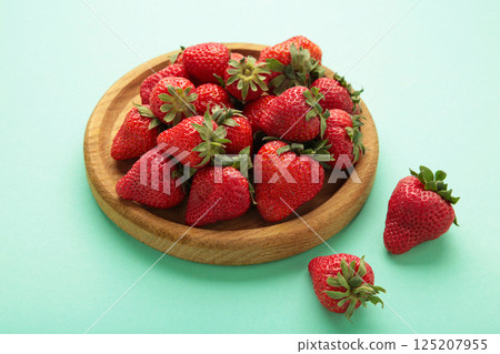 Red fresh strawberry in wooden bowl on mint background Red fresh strawberry in wooden bowl on mint background 125207955