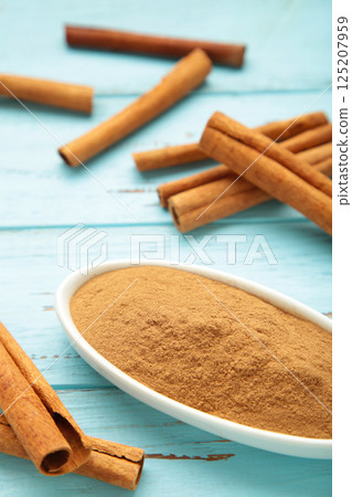Cinnamon sticks and powder in bowl on blue background. Vertical photo Cinnamon sticks and powder in bowl on blue background. Vertical photo 125207959