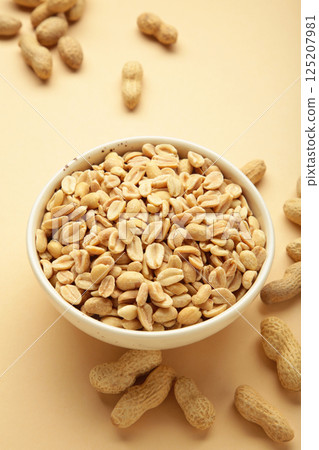Roasted peanuts on white bowl on beige background Roasted peanuts on white bowl on beige background 125207981