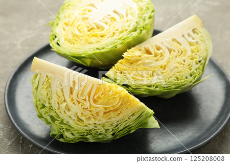 Fresh cut cabbages on dark plate on grey background Fresh cut cabbages on dark plate on grey background 125208008