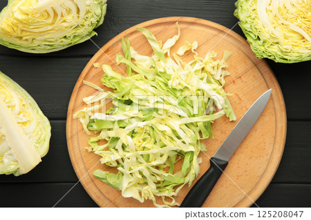 Fresh cut cabbages on cutting board on black wooden background Fresh cut cabbages on cutting board on black wooden background 125208047