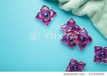 Laundry capsules with mint towel on blue background. Laundry detergent for washing clothes in a washing machine. 125208050