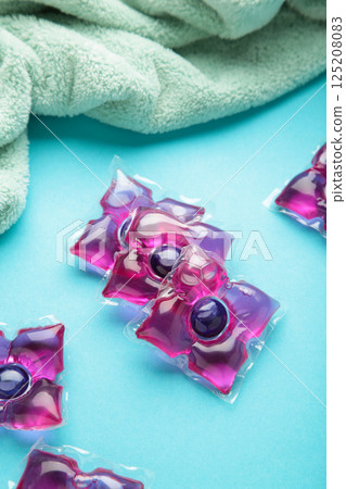 Laundry capsules with mint towel on blue background. Laundry detergent for washing clothes in a washing machine. Vertical photo 125208083