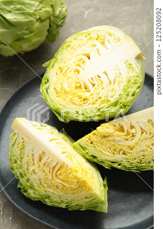 Fresh young shredded cabbage on dark plate. Vegetables for cutting spring salad. Vegan food, diet, vitamins 125208092