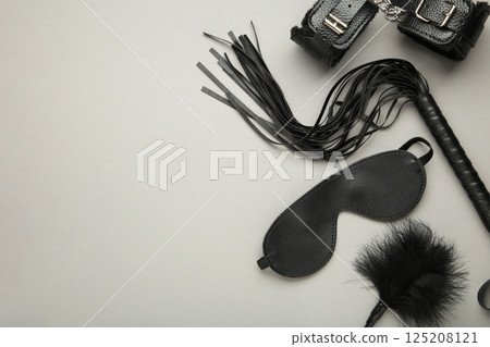 Set of erotic toys for BDSM on grey background. The game of sexual slavery with a whip, gag and leather blindfold. Intimate sex games 125208121