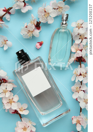Bottles of woman perfume on blue background with spring apricot and cherry flowers. Bottles of woman perfume on blue background with spring apricot and cherry flowers. 125208157