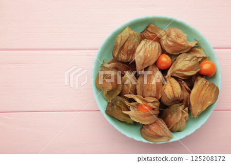 Physalis peruviana fruit on mint plate on pink background. Physalis peruviana fruit on mint plate on pink background. 125208172