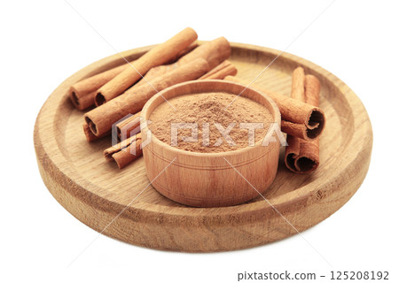 Cinnamon sticks and powder in bowl isolated on white background. Cinnamon sticks and powder in bowl isolated on white background. 125208192