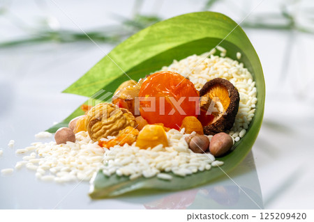 新鮮綠葉包裹著製作粽子多樣化的餡料 新鮮綠葉包裹著製作粽子多樣化的餡料 125209420