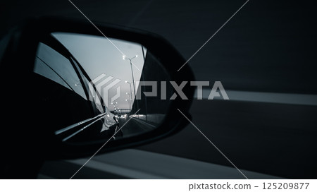 Car side mirror reflecting blurred road lights in black and white mood Car side mirror reflecting blurred road lights in black and white mood 125209877