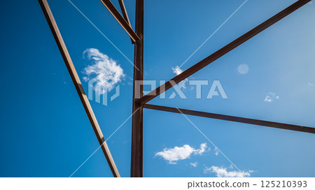 Industrial Steel Framework Construction with Geometric Patterns Against Bright Blue Sky 125210393