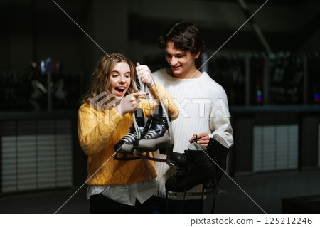 Excited friends preparing for ice skating at the rink in winter 125212246