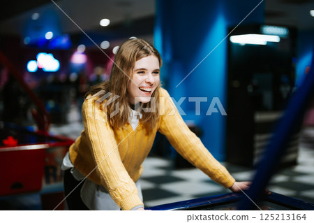 Young woman enjoys fun arcade game in lively entertainment center 125213164