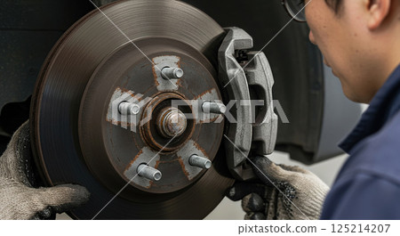 A mechanic inspecting the brakes 125214207