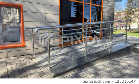 Ramp for entering building for people with disabilities and parents with baby carriage. Convenient entrance with lifting ramp for comfortable ascent. Accessible environment in modern city Ramp for entering building for people with disabilities and parents with baby carriage. Convenient entrance with lifting ramp for comfortable ascent. Accessible environment in modern city 125216147
