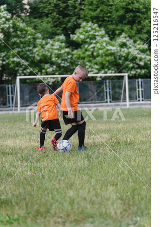 Two boys competing for soccer ball on grassy field. Two boys competing for soccer ball on grassy field. 125216547