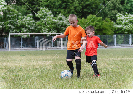 Two boys fighting for ball during outdoor soccer game. Two boys fighting for ball during outdoor soccer game. 125216549