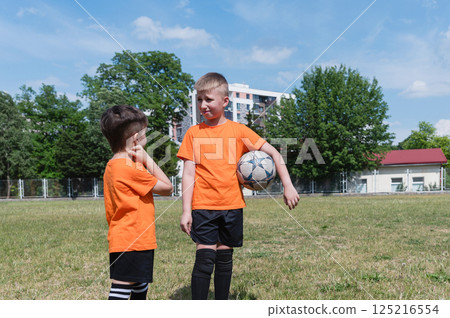 Two boys talking during soccer break on sunny field. Two boys talking during soccer break on sunny field. 125216554