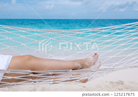 A young woman  is lying in a hammock near the ocean 125217675