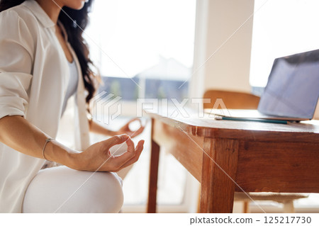Asian woman in white clothes is sitting on chair in lotus position and meditating 125217730