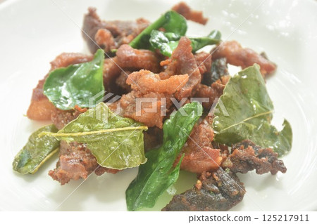 fried crispy salty fermenting pork meat with lemon leaf and chili on plate  125217911
