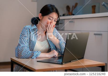 Young woman tired from working from home for long hours Young woman tired from working from home for long hours 125218240