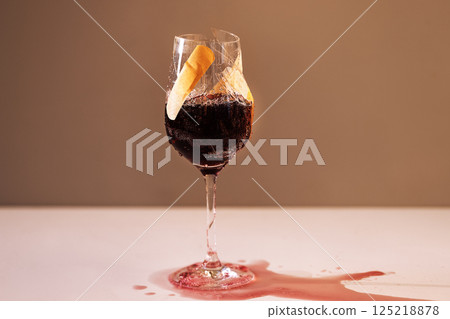 Close-up of a cracked glass of red wine. A broken goblet of bright juice covered with a plaster. A leaking cup with a red drink. Close-up of a cracked glass of red wine. A broken goblet of bright juice covered with a plaster. A leaking cup with a red drink. 125218878