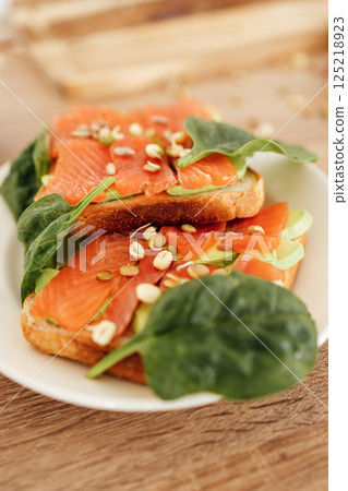 Fresh smoked salmon on toast with spinach and seeds Fresh smoked salmon on toast with spinach and seeds 125218923