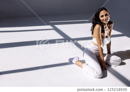 Studio fashion portrait of a charming young woman sitting with her eyes closed 125218930